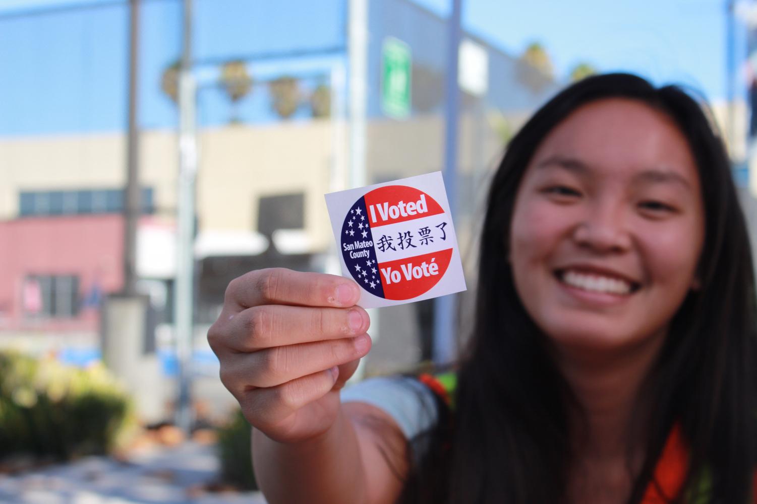 Madison Pelarca, a volunteer at the polls and a student at Carlmont High School, displays an