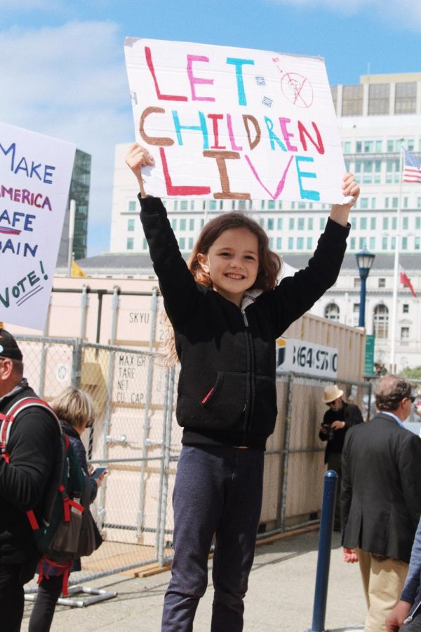 Elementary schooler Tiana holds up a sign that reads Let Children Live.