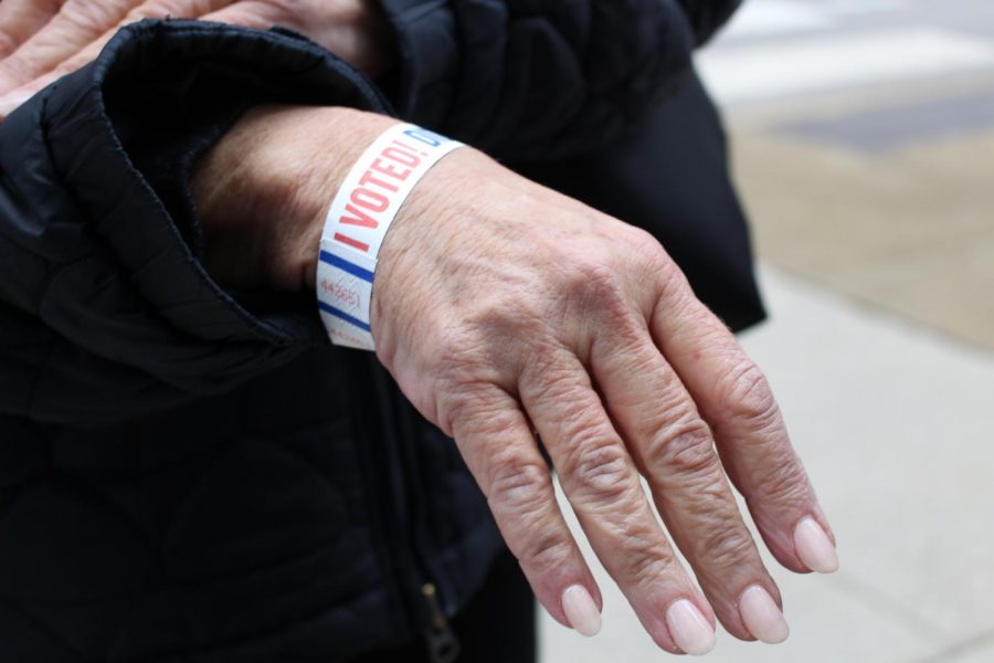 A woman proudly displays her “I voted” wristband.