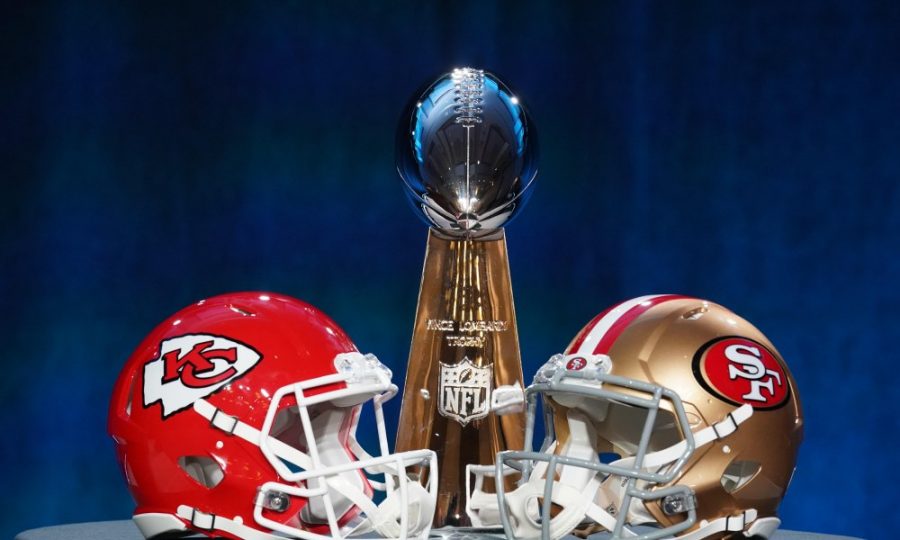 The two teams helmets line up with the Lombardi Trophy in the background.