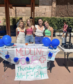 Medline Club co- presidents and co-vice president stand in front of their table at club rush.