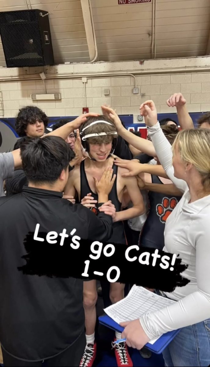 Teammates gather around sophomore wrestler Casimir Berke to ready him for his upcoming match in the Mills Dual