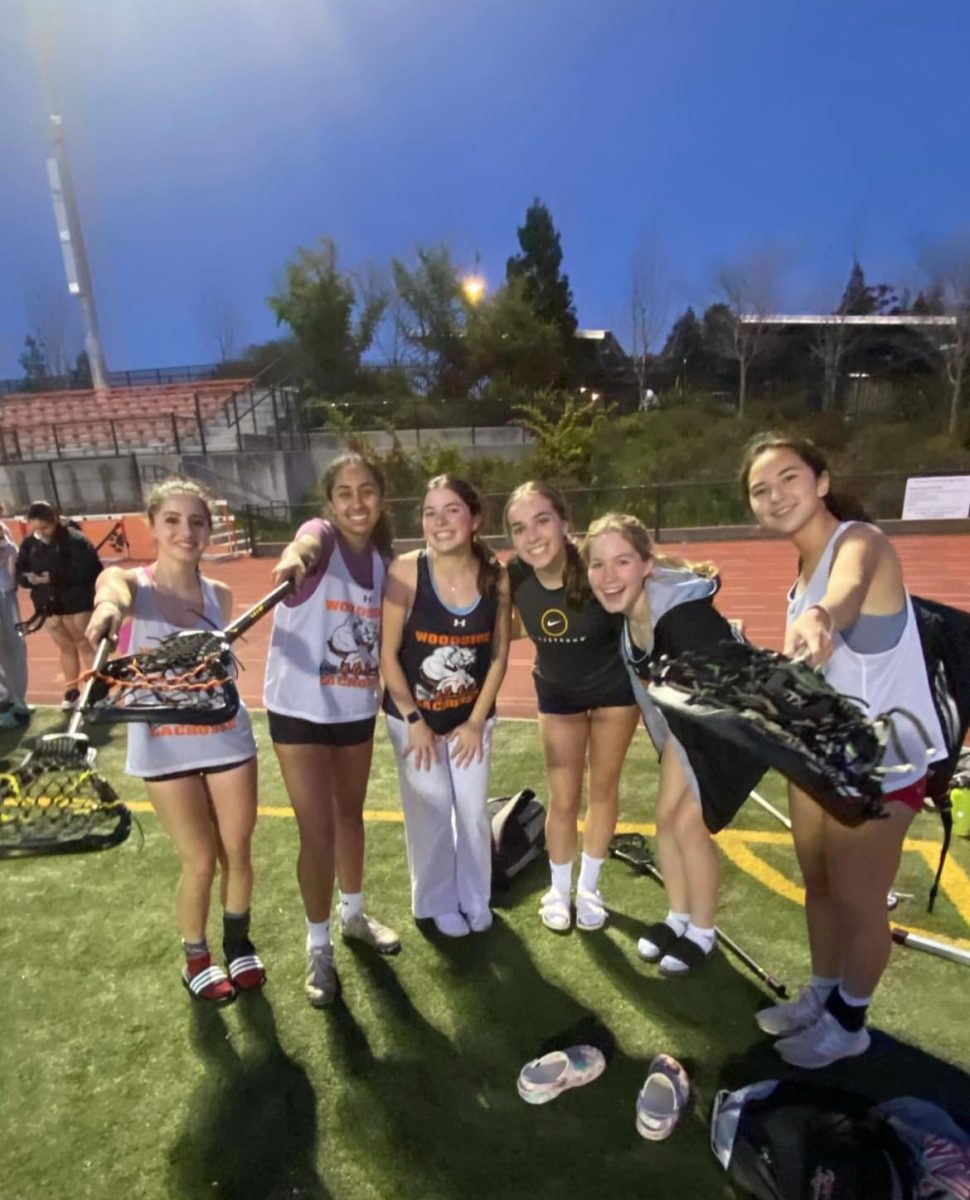 Varsity girls lacrosse players pose for the camera after practice.