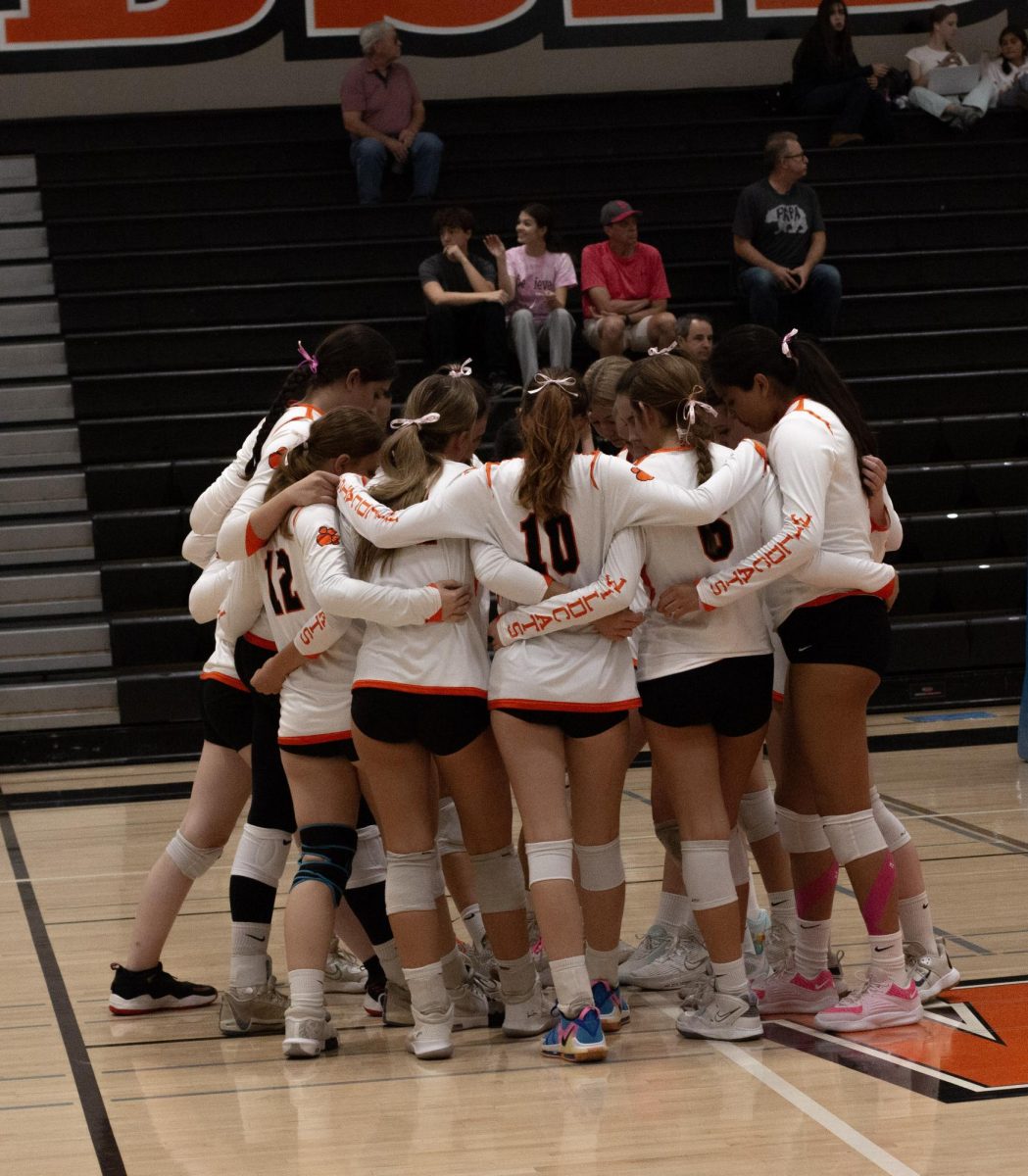 Team huddle with feet in the middle before the game starts. Pink ribbons tied in ponytails in support of breast cancer awareness.