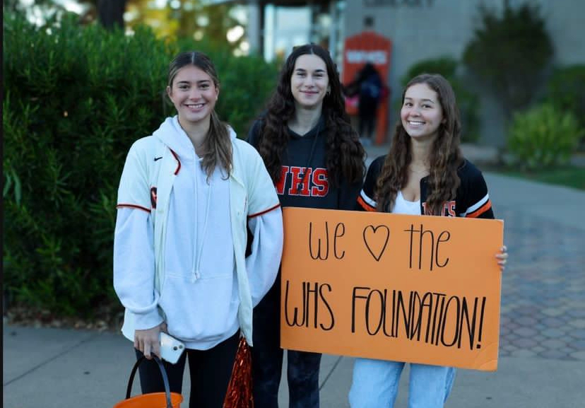 Photo of Sophia Delis, Lena Argenti and Alexia Alpert holding up a poster that says, “We love the Woodside High School Foundation.”