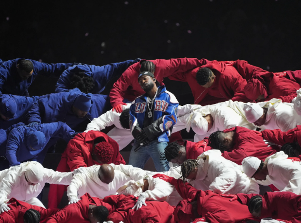 Kendrick Lamar stands center, surrounded by dancers forming an American flag.