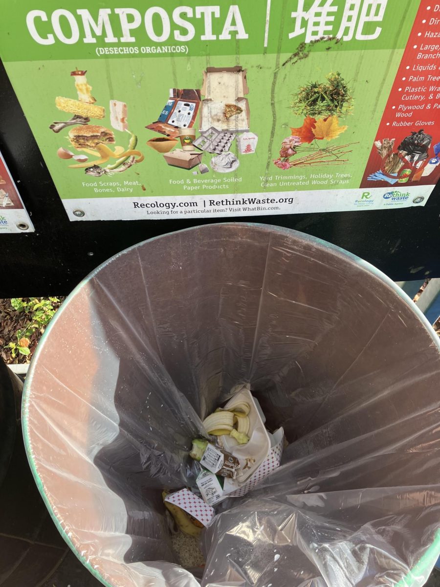 A compost bin in the quad with a sign in multiple languages