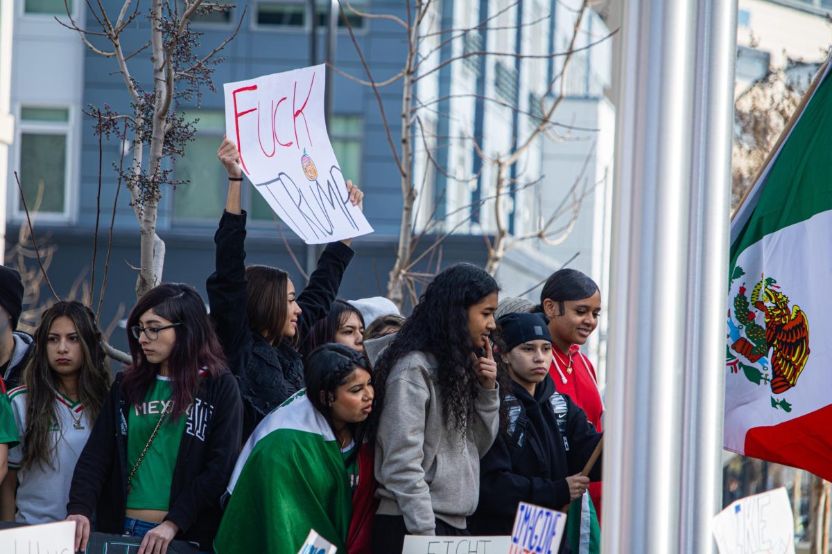 Students protest and hold signs with anti-Trump and anti-ICE messages. One student waves the Mexican flag.