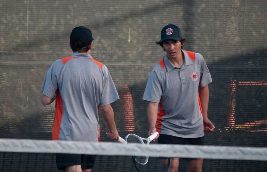 Evan Pandes and Cruz Nieva tapping rackets after scoring a point.