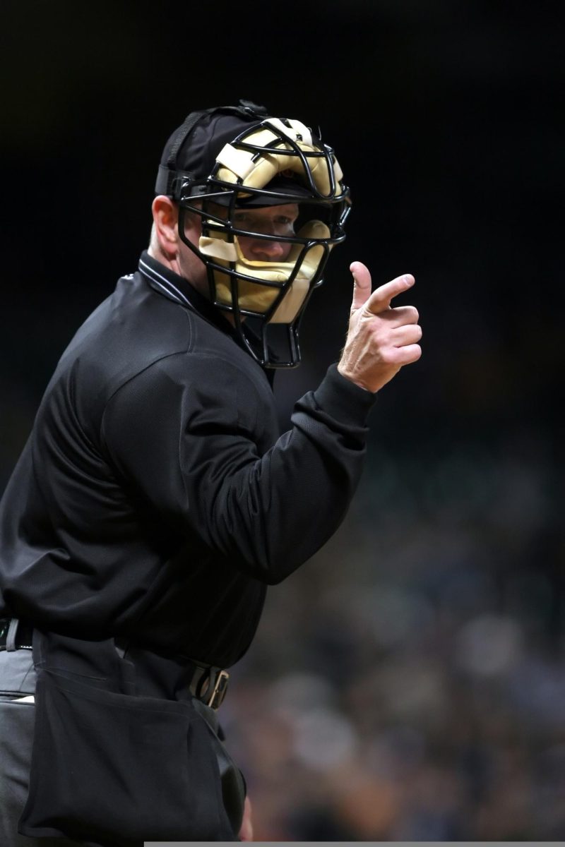 A baseball umpire making a hand signal during a game of baseball.